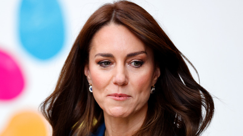 Kate Middleton frowning and looking to the side with windblown brunette hair