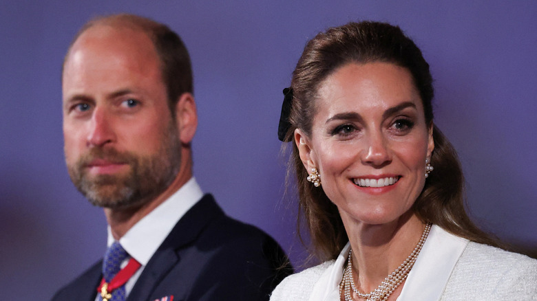 Kate Middleton smiling, with Prince William in the background