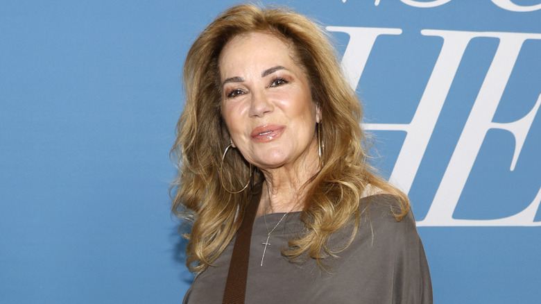 Kathie Lee Gifford wears large hoop earrings and gray top in 2024.