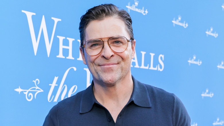 Kavan Smith posing at a Hallmark event in glasses and a navy shirt