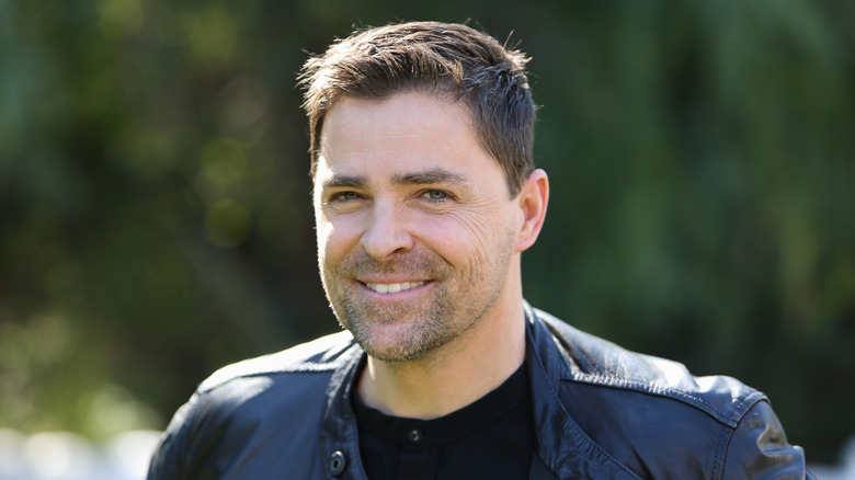 Kavan Smith smiling while posing for photos in a black shirt and leather jacket