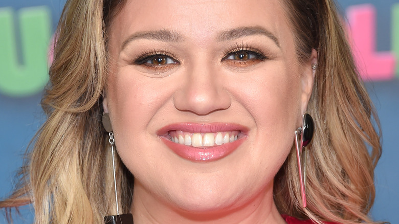 Kelly Clarkson smiling with long earrings