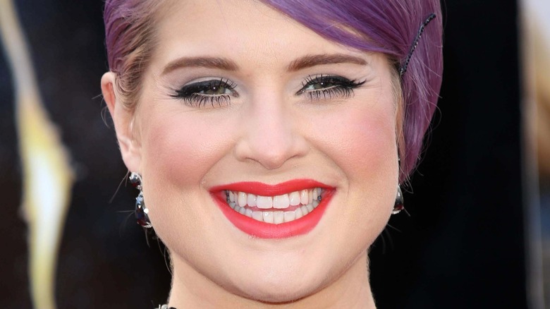 Kelly Osbourne smiling, wearing red lipstick