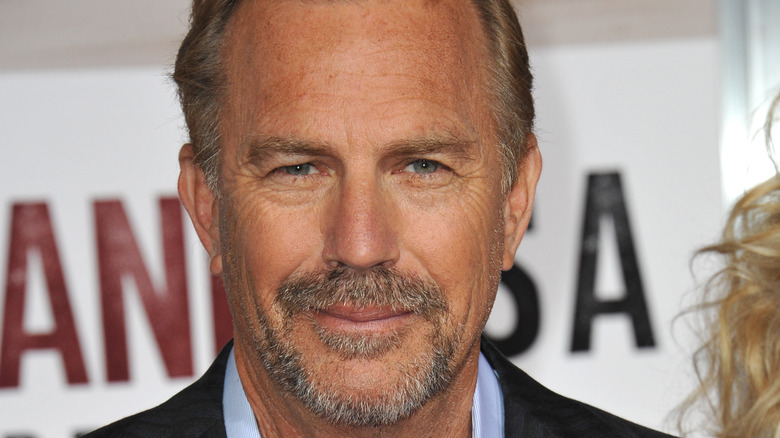 Kevin Costner poses in a blue dress shirt and blazer