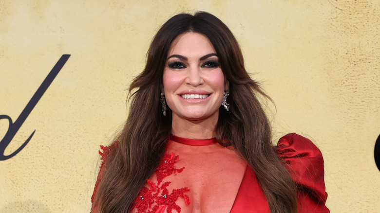 Kimberly Guilfoyle smiling in red lace dress