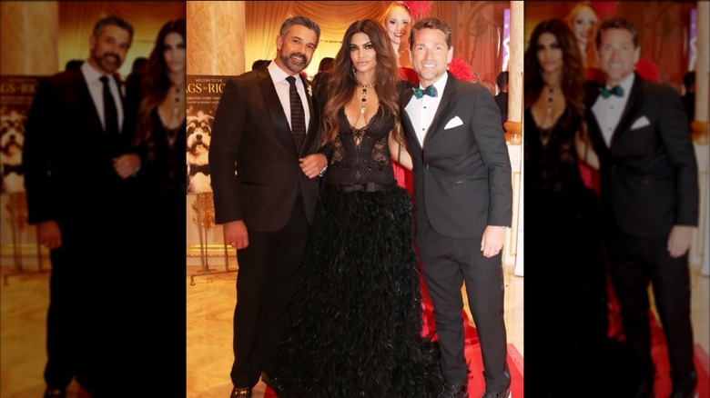 Kimberly Guilfoyle in a low cut feathery long dress posing with two friends