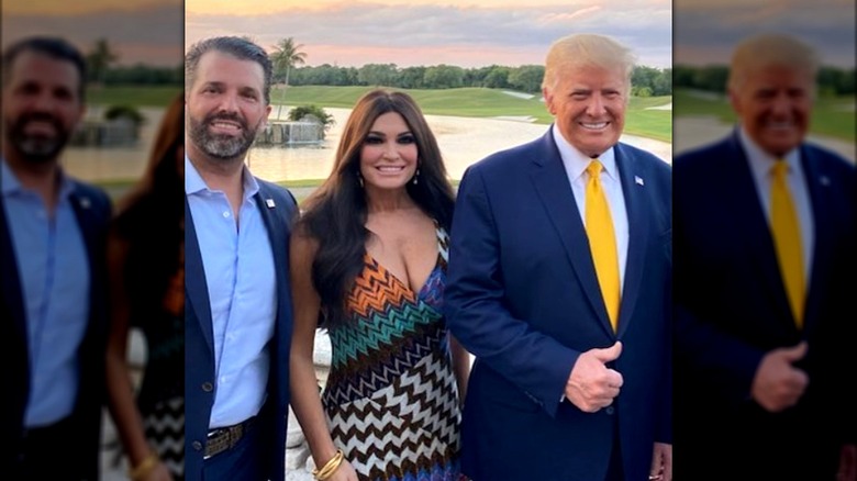 Kimberly Guilfoyle smiling between Donald Trump Jr and Donald Trump