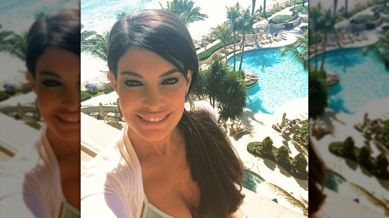 Kimberly Guilfoyle smiling with a long ponytail over her shoulder and a resort pool in the background.