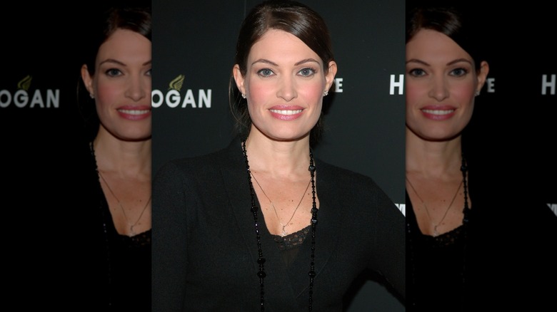 Kimberly Guilfoyle with hair up, wearing a black outfit and long beaded necklace.