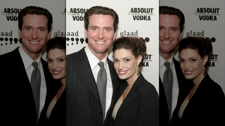 Kimberly Guilfoyle and Gavin Newsom smiling and posing in dark outfits.
