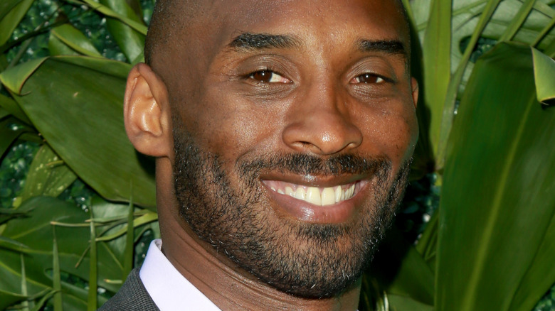 Kobe Bryant in front of green leaves