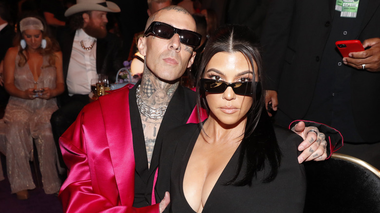 Travis Barker with his arm around Kourtney Kardashian