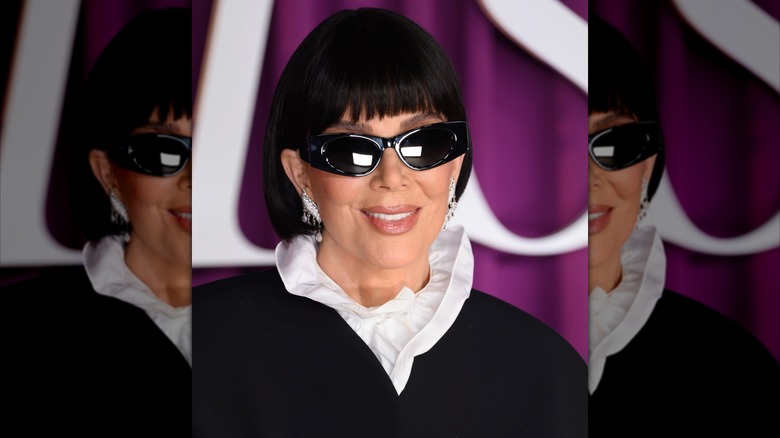 Kris Jenner wearing cat-eye sunglasses and a white shirt with a high ruffled collar at the premiere for "All's Fair" in 2025.