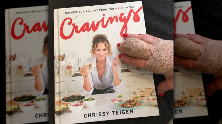 Kris Jenner's bandaged hand holds Chrissy Teigen's cookbook