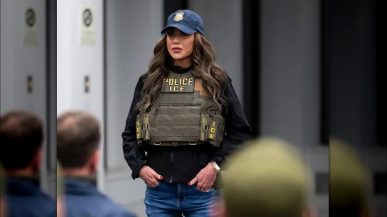 Kristi Noem wearing a baseball cap and Police vest