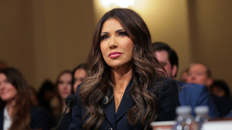 Kristi Noem listening in court while wearing a black blazer