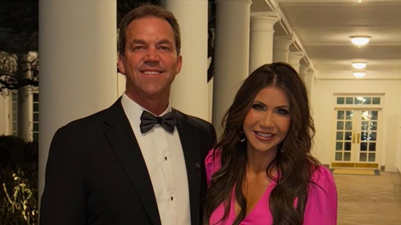 Bryon Noem in a tux and Kristi Noem in a fuchsia dress posing at the White House.