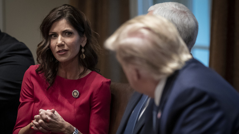 Kristi Noem with long hair gazing at Donald Trump