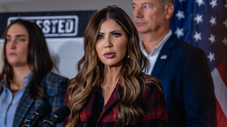 Kristi Noem standing in front of a flag