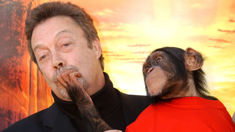 Tim Curry holding Jake the Monkey at 'The Wild Thornberrys Movie' premiere.