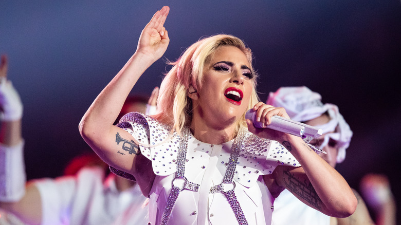 Lady Gaga singing into a microphone wearing bedazzled football pads