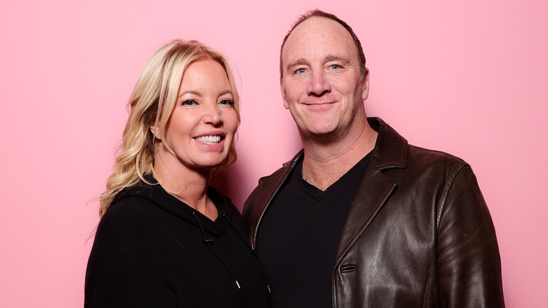 Jeanie Buss poses with Jay Mohr on pink background