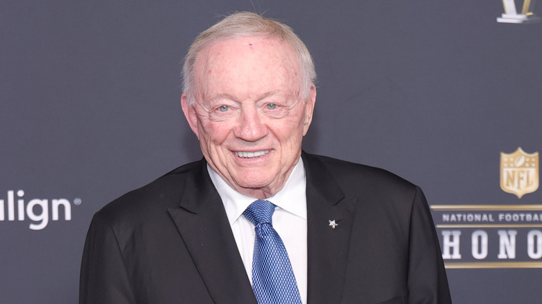 Jerry Jones wearing a black tuxedo and blue tie at a red carpet event