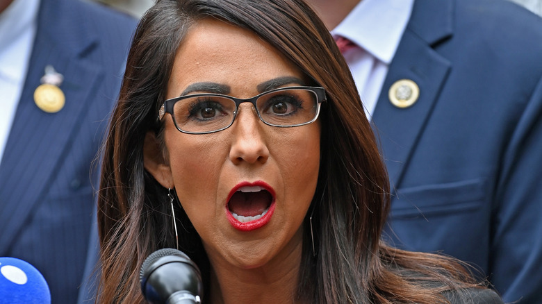 Lauren Boebert shouting into a microphone in red lipstick