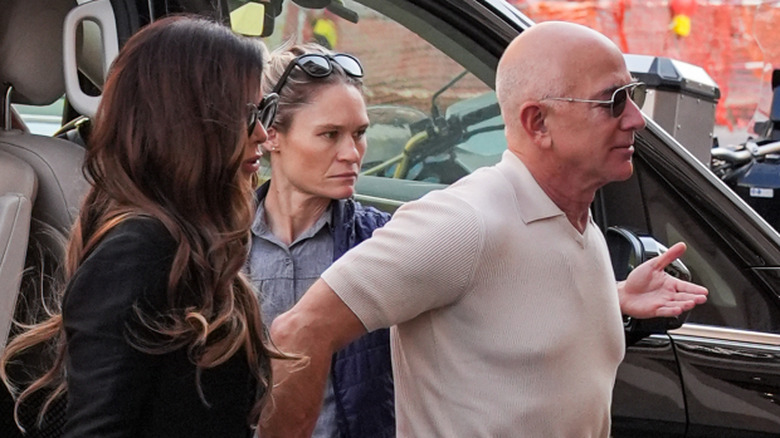 Lauren Sanchez walking with Jeff Bezos with a noticeable tan line around his forehead