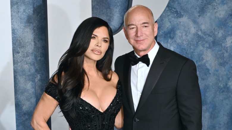 Sporting an all-black look, Lauren Sanchez leans toward a smiling Jeff Bezos.