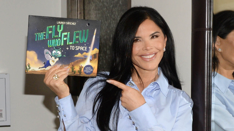 Lauren Sanchez smiling and pointing at her book The Fly Who Flew to Space