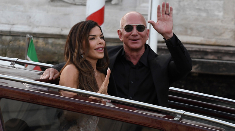 Lauren Sanchez and Jeff Bezos sitting and waving on a boat