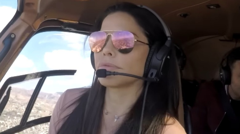 Lauren Sánchez wears a pair of reflective shades and a headset while flying a helicopter.
