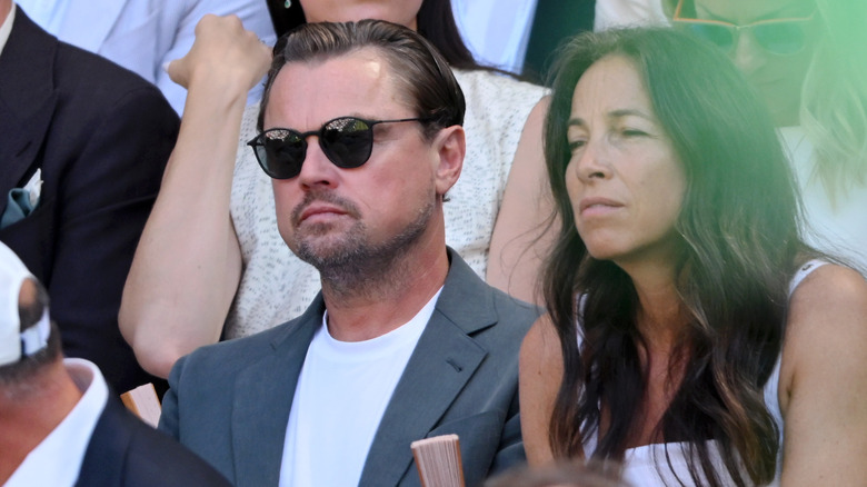 Leonardo DiCaprio sitting down at the Wimbledon 2025 game while wearing dark sunglasses.