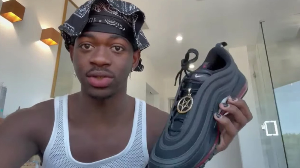 Lil Nas X holding up shoe with pentagram