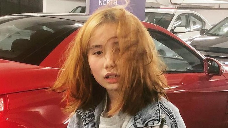 Lil Tay in front of red car