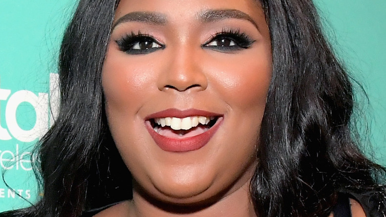 Lizzo smiles in front of teal background