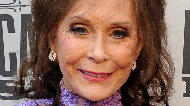 Loretta Lynn smiles in purple dress