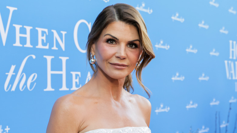 Lori Loughlin looking at the camera while posing at an event in front of a light-blue background