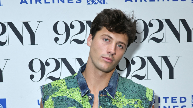 Rob Rausch posing on a red carpet in front of a light blue background