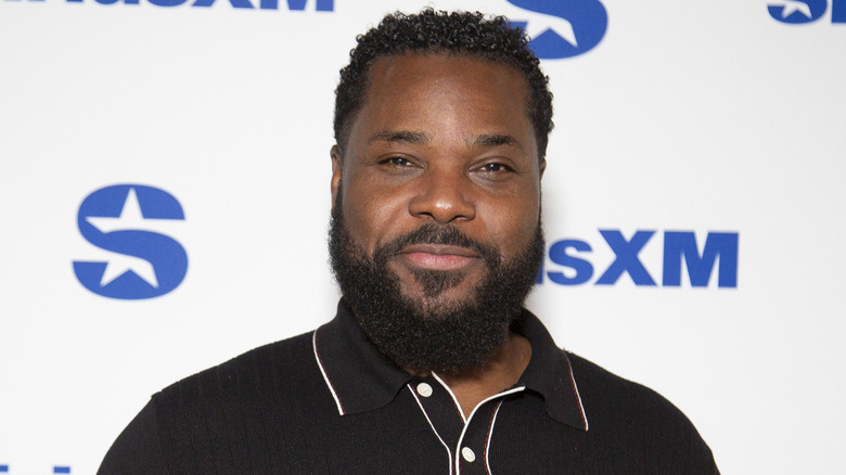 Malcolm Jamal Warner smiling and wearing a black collared shirt on the red carpet