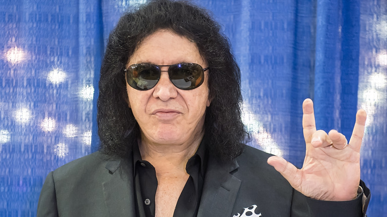 Gene Simmons posing and making a hand sign