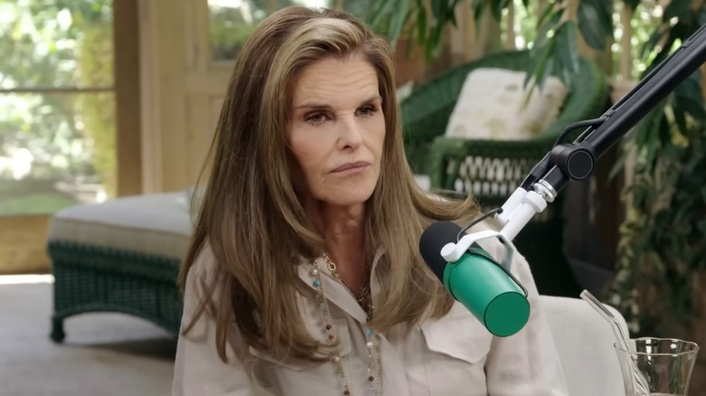 Maria Shriver makes a gloomy face while seated behind a microphone