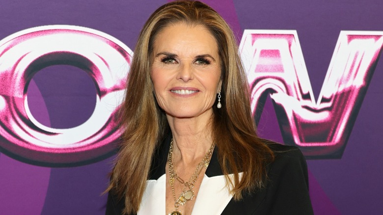 Dressed in a black and white suit and golden jewelry, Maria Shriver flashes a wide smile