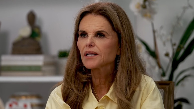 Wearing a collared yellow shirt, Maria Shriver looks away from the camera while speaking