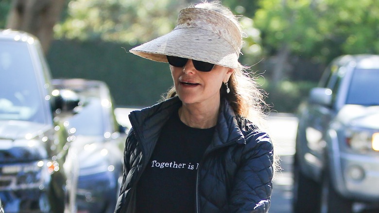 Dressed in an all black outfit and a wide-brimmed hat, Maria Shriver walks while gazing downward