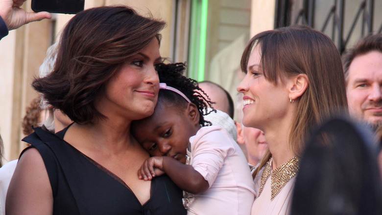 Mariska Hargitay and Hilary Swank smiling at each other while Mariska holds Amaya Hermann