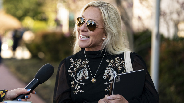 Marjorie Taylor Greene smiles while speaking to a reporter.
