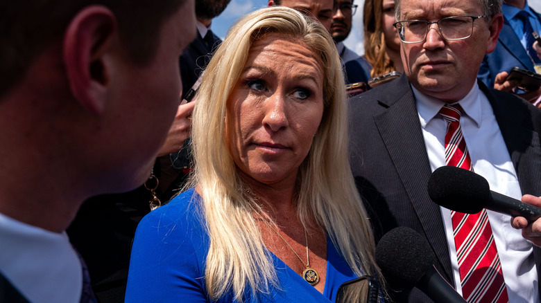 Marjorie Taylor Greene makes a face while speaking to the press in 2024