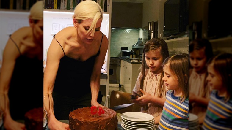 Alexis Stewart presenting a birthday cake for a friend alongside her two children.